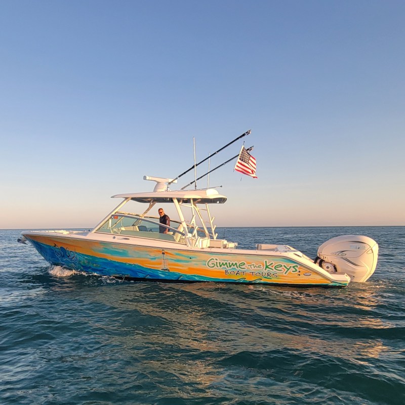 Colorful boat with US flag on the ocean at sunset.