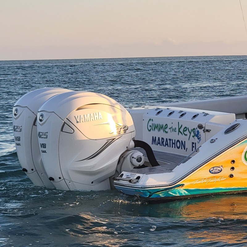 Back of a boat with twin Yamaha V8 outboard motors in the ocean at sunset.