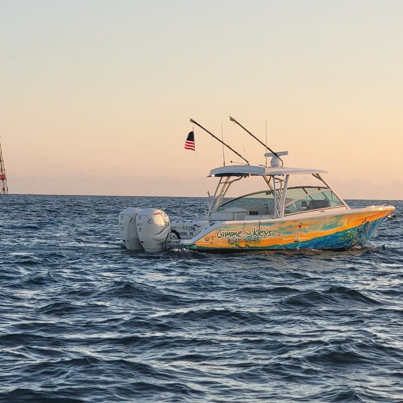 Vibrant boat on ocean near a metal lighthouse structure at sunset.